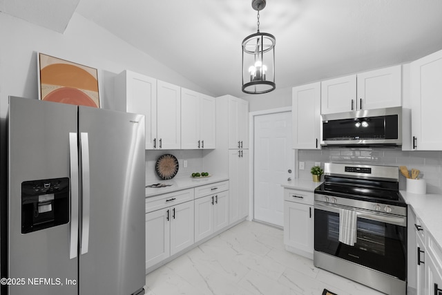 kitchen featuring lofted ceiling, white cabinetry, decorative light fixtures, stainless steel appliances, and decorative backsplash