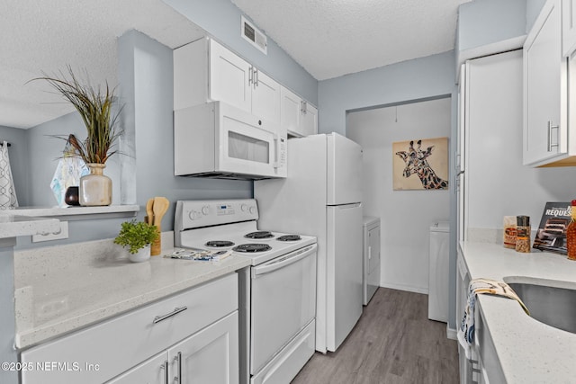 kitchen featuring white cabinetry, white appliances, independent washer and dryer, and a textured ceiling