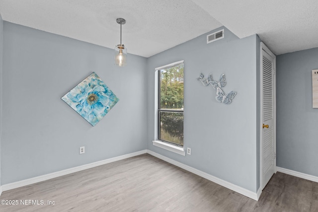 spare room featuring hardwood / wood-style flooring and a textured ceiling