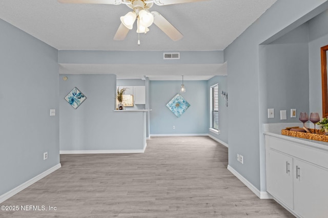 unfurnished living room featuring ceiling fan, a textured ceiling, and light hardwood / wood-style floors