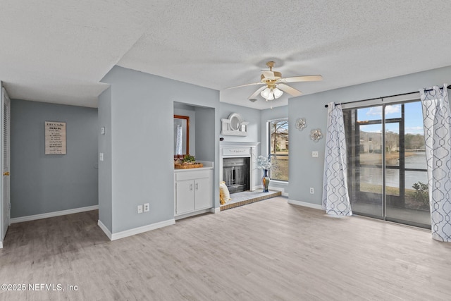 unfurnished living room featuring a textured ceiling, ceiling fan, and light wood-type flooring