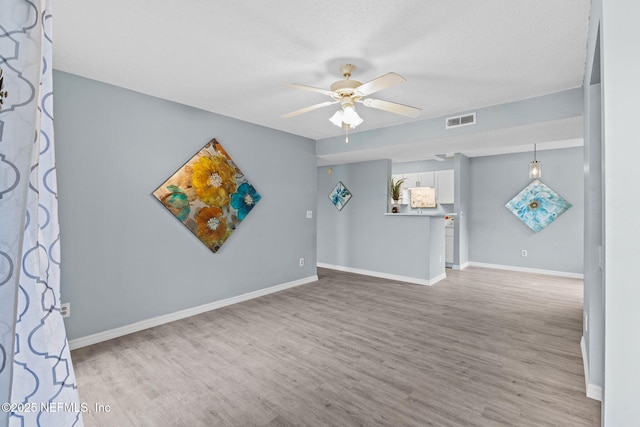 spare room with a textured ceiling, ceiling fan, and light hardwood / wood-style floors