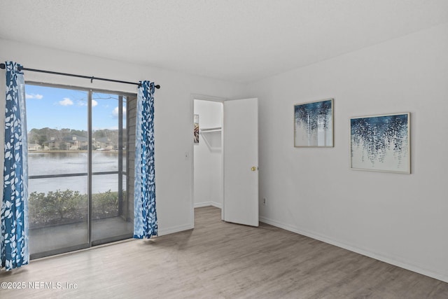 empty room with a water view, a textured ceiling, and light hardwood / wood-style flooring