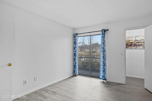 spare room featuring hardwood / wood-style floors and a textured ceiling