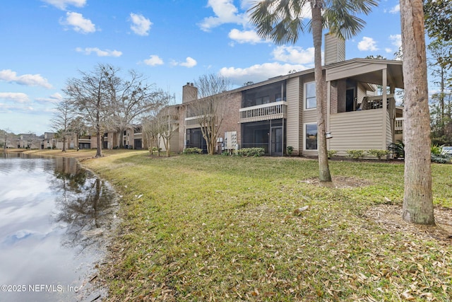 rear view of property with a water view and a lawn