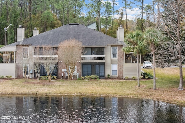 rear view of property featuring a water view and a lawn