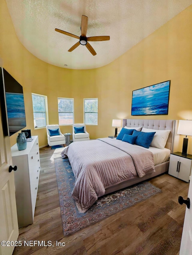 bedroom with hardwood / wood-style flooring, ceiling fan, and a textured ceiling