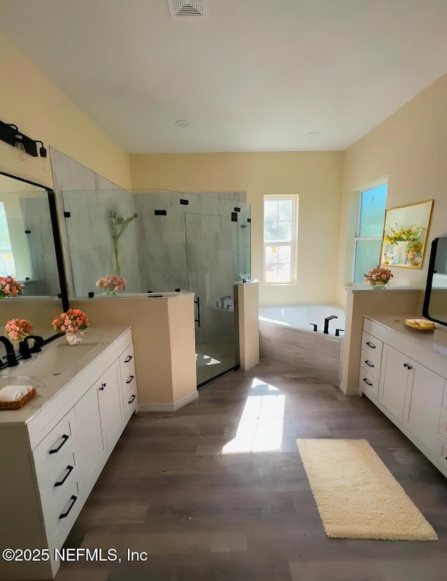 bathroom featuring plus walk in shower, hardwood / wood-style floors, and vanity