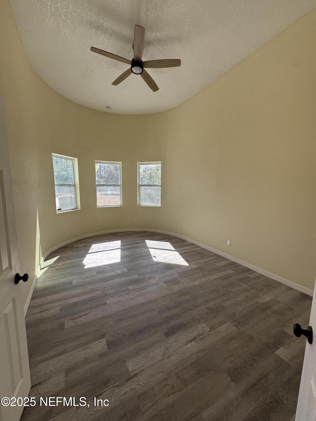 spare room with ceiling fan, plenty of natural light, dark wood-type flooring, and a textured ceiling