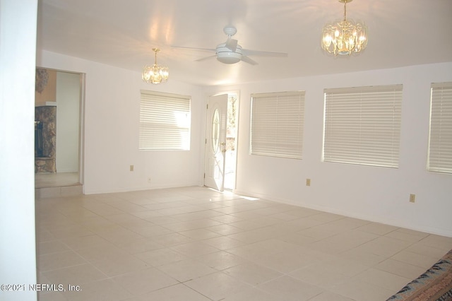 empty room with ceiling fan with notable chandelier and light tile patterned floors