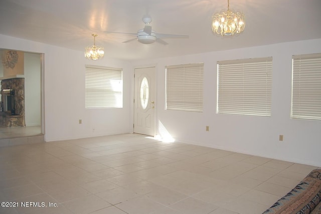 tiled entrance foyer with ceiling fan with notable chandelier