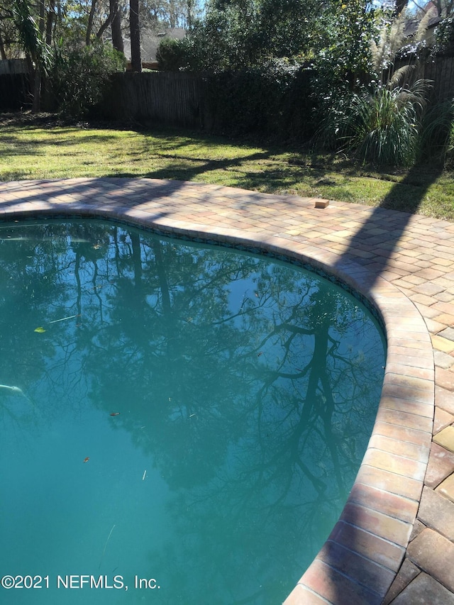 view of pool with a patio area and a lawn