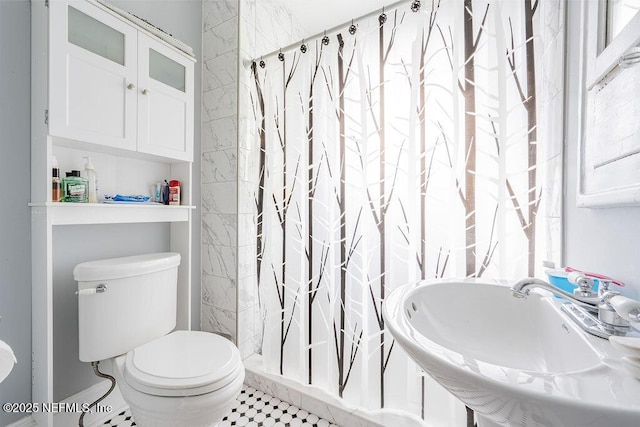 bathroom with sink, curtained shower, and toilet