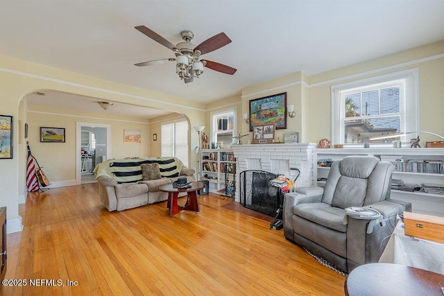 living room with ceiling fan, a fireplace, and light hardwood / wood-style flooring