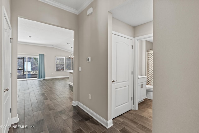 hall featuring an inviting chandelier, ornamental molding, and lofted ceiling