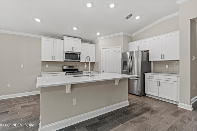 kitchen with a kitchen island with sink, white cabinetry, and appliances with stainless steel finishes