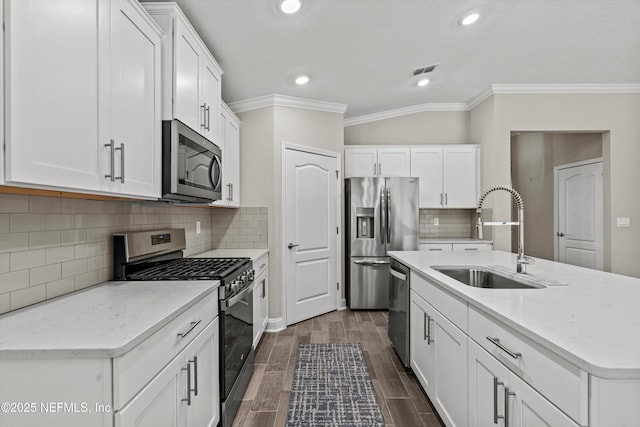 kitchen with appliances with stainless steel finishes, sink, white cabinets, a kitchen island with sink, and light stone countertops