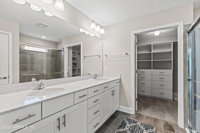 bathroom featuring vanity, a textured ceiling, and a shower with shower door