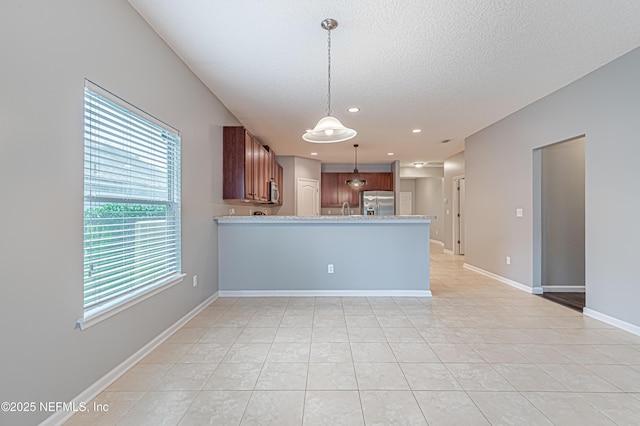 kitchen featuring appliances with stainless steel finishes, hanging light fixtures, a textured ceiling, light tile patterned flooring, and kitchen peninsula