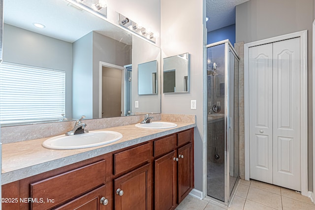 bathroom featuring vanity, a shower with door, tile patterned flooring, and a textured ceiling