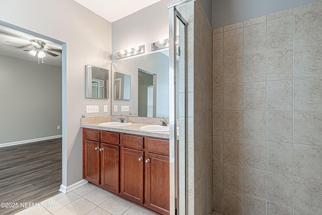 bathroom with vanity, tile patterned flooring, ceiling fan, and tiled shower