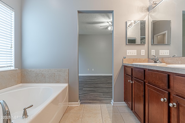 bathroom featuring tile patterned floors, a bathing tub, a textured ceiling, and vanity