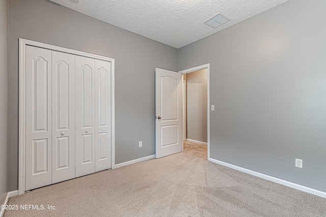 unfurnished bedroom featuring light colored carpet, a closet, and a textured ceiling