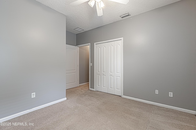 unfurnished bedroom with ceiling fan, light colored carpet, a closet, and a textured ceiling