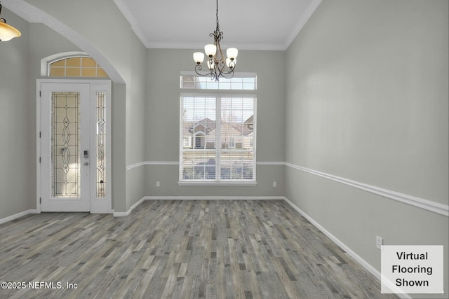 unfurnished dining area featuring an inviting chandelier, wood finished floors, baseboards, and ornamental molding