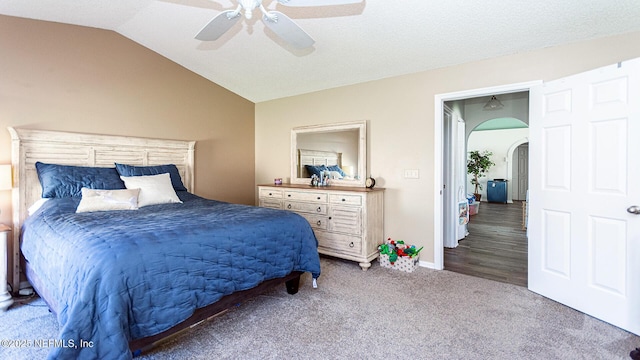 carpeted bedroom featuring lofted ceiling, ceiling fan, arched walkways, and baseboards