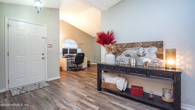 foyer featuring lofted ceiling, baseboards, and wood finished floors