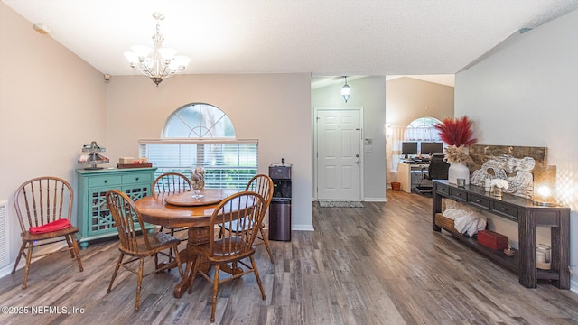 dining space with a chandelier, vaulted ceiling, baseboards, and wood finished floors