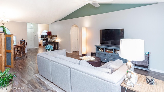 living area with arched walkways, vaulted ceiling, wood finished floors, baseboards, and ceiling fan with notable chandelier