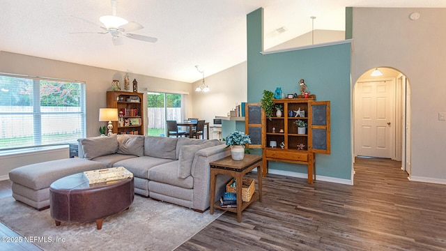 living area featuring arched walkways, plenty of natural light, wood finished floors, and baseboards