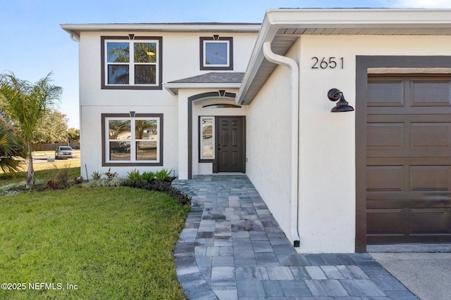 entrance to property featuring a garage and a lawn