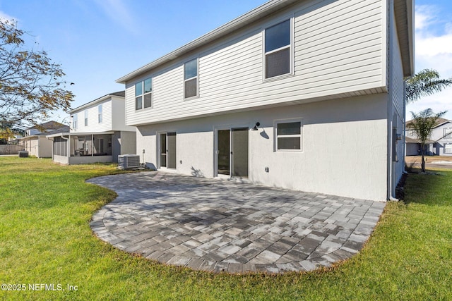 back of property with central AC unit, a patio area, a sunroom, and a lawn