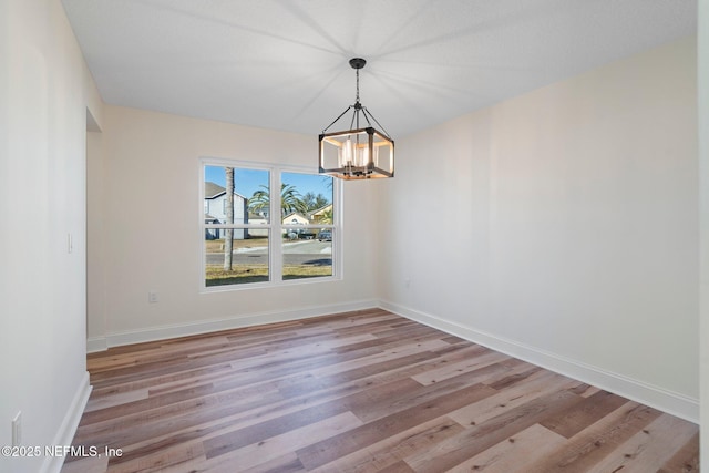 unfurnished dining area with an inviting chandelier and light wood-type flooring