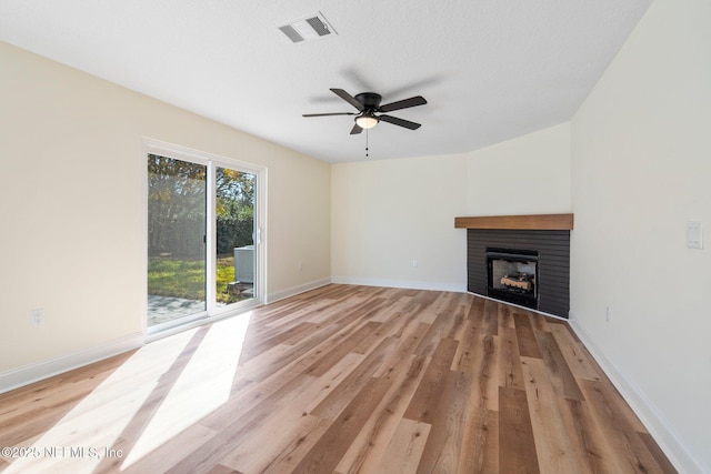 unfurnished living room featuring ceiling fan, a fireplace, a textured ceiling, and light wood-type flooring