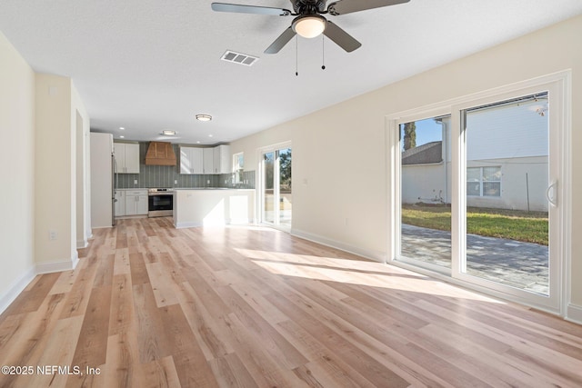 unfurnished living room featuring ceiling fan, a healthy amount of sunlight, and light hardwood / wood-style floors