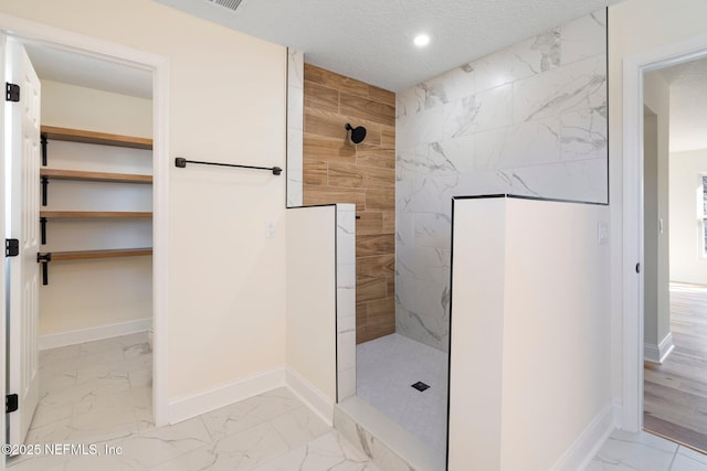 bathroom featuring a tile shower and a textured ceiling