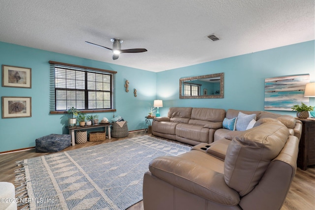 living room featuring ceiling fan, a textured ceiling, and light wood-type flooring