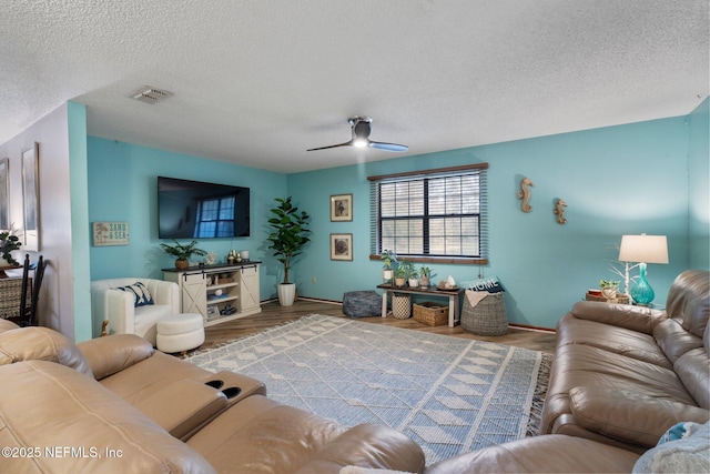 living room with ceiling fan, a textured ceiling, and light hardwood / wood-style floors