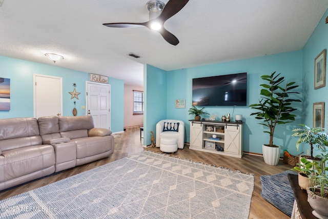 living room featuring ceiling fan, wood-type flooring, and a textured ceiling