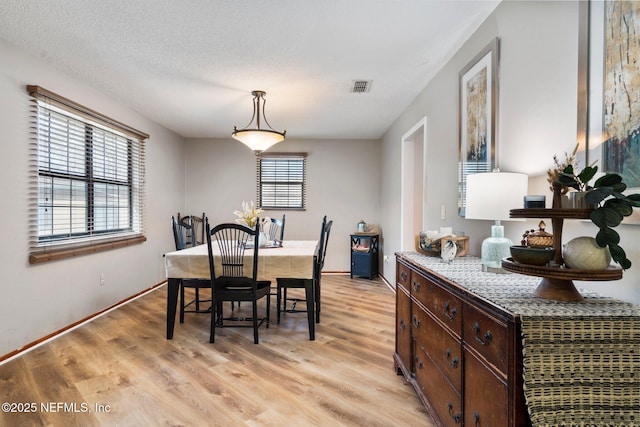 dining space with a textured ceiling and light wood-type flooring