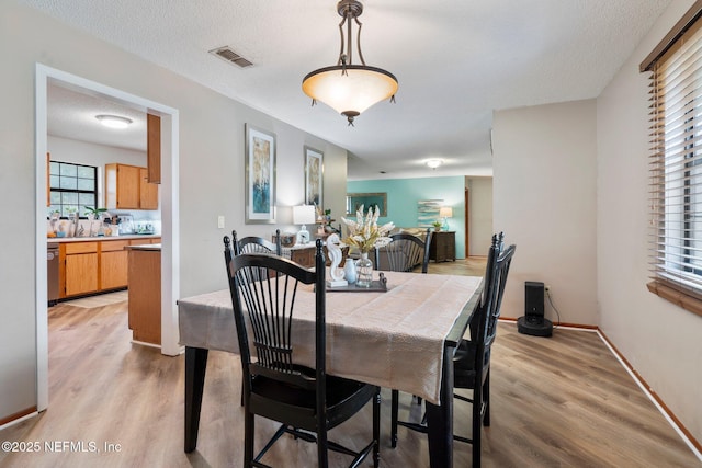 dining area featuring light hardwood / wood-style floors and a textured ceiling