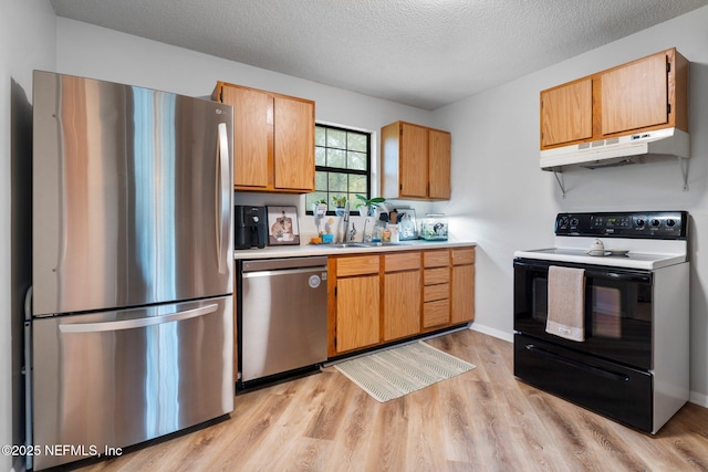 kitchen with sink, stainless steel appliances, a textured ceiling, and light wood-type flooring