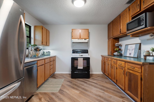 kitchen with sink, light hardwood / wood-style flooring, a textured ceiling, and appliances with stainless steel finishes