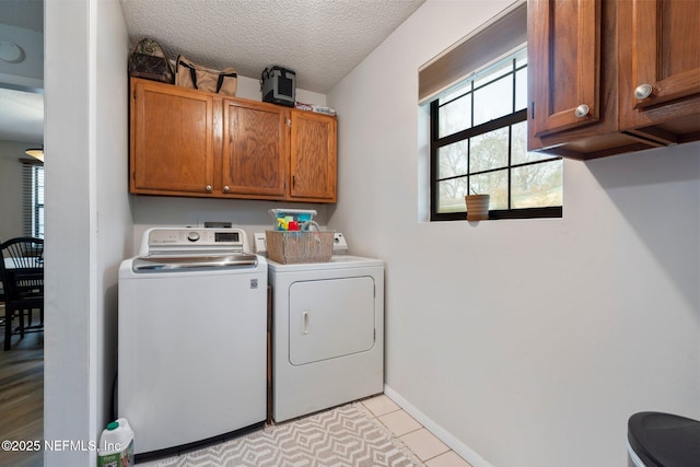 laundry room with washer and clothes dryer, cabinets, a textured ceiling, and light tile patterned flooring