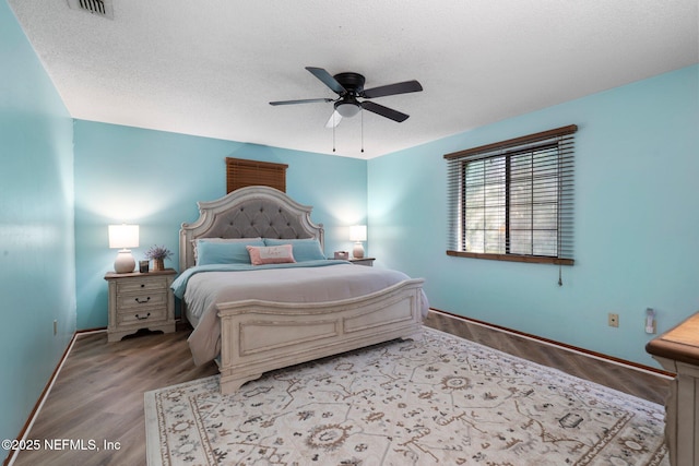 bedroom featuring ceiling fan, light hardwood / wood-style flooring, and a textured ceiling