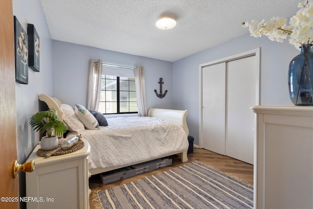 bedroom with dark wood-type flooring, a closet, and a textured ceiling